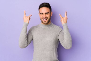 Mor arka planda izole edilmiş genç beyaz adam boynuzlarını devrim konsepti olarak gösteriyor..