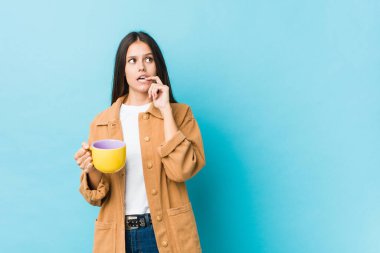 Kafkasyalı genç bir kadın elinde kahve fincanı tutarken rahatlamış fotokopi odasına bakan bir şey düşünüyor..