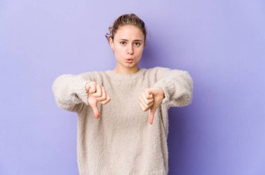 Mor arka planda beyaz bir kadın baş parmağını aşağı gösteriyor ve hoşlanmadığını ifade ediyor..