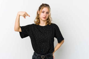 Beyaz arka plandaki genç beyaz kadın bir gömlek fotokopisini elle işaret ediyor, gururlu ve kendinden emin.