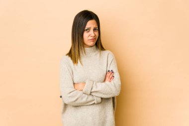 Bej arka planda izole edilmiş genç bir kadın kameraya alaycı bir ifadeyle bakıyor..