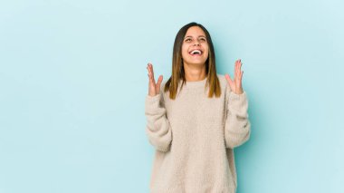 Mavi arka planda soyutlanmış genç bir kadın kahkahalarla gülüyor..