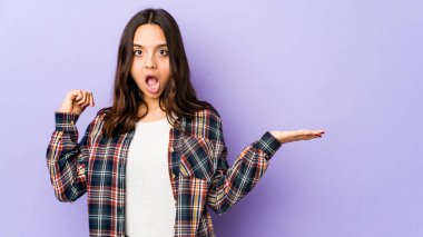 Genç, melez, İspanyol bir kadın avucunun içinde fotokopi alanı tutuyor, el üstünde tutuyor. Şaşırmış ve mutlu..