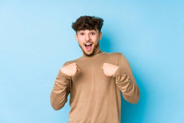 İzole edilmiş genç Arap adam şaşırmış, parmağıyla işaret ediyor, geniş bir gülümsemeyle..