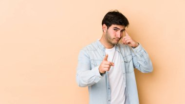 Bej arka planda izole edilmiş genç bir adam parmağıyla tapınağı işaret ediyor, düşünüyor ve bir göreve odaklanıyor..