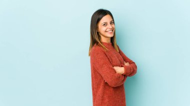 Mavi arka planda izole edilmiş genç bir kadın mutlu, güler yüzlü ve neşeli.