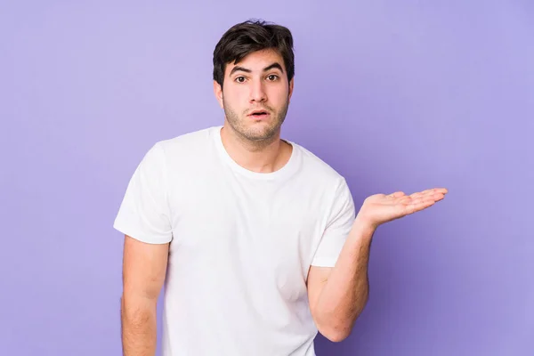Junger Mann Auf Violettem Hintergrund Beeindruckt Mit Kopierraum Auf Handfläche — Stockfoto