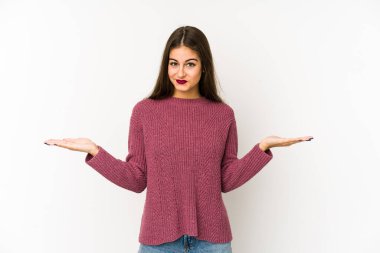 Beyaz arka planda izole genç beyaz kadın kollarıyla ölçek yapar, mutlu ve kendinden emin hisseder..