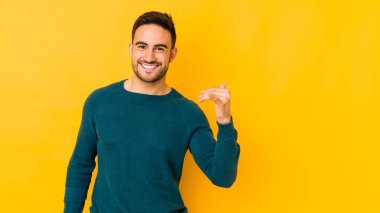 Sarı fırında izole edilmiş genç beyaz bir adam bir şeye gülüyor, elleriyle ağzını kapatıyor..