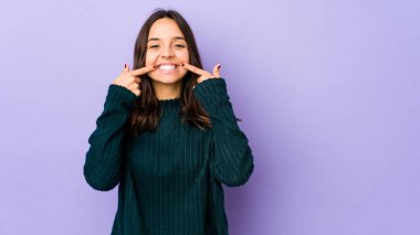 Genç, melez, ispanyol bir kadın. Tek başına gülüyor, parmaklarını ağzına doğrultuyor..