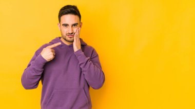 Sarı fırında izole edilmiş genç beyaz bir adam güçlü bir diş ağrısı ve azıdişi ağrısı var..