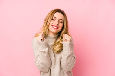 Süveter giyen genç sarışın kadın kendini mutlu ve başarılı hissediyor. Zafer konsepti.