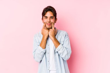 Pembe arka planda poz veren beyaz bir genç iki seçenek arasında kuşkulanıyor..