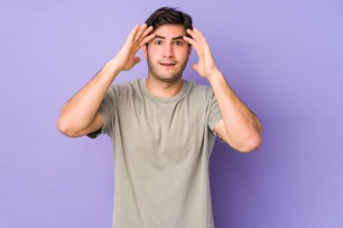 Mor arka planda izole genç bir adam hoş bir sürpriz alıyor, heyecanlı ve el kaldırıyor..
