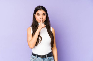 Mor arka planda izole edilmiş genç Hintli bir kadın ya sır saklıyor ya da sessizlik istiyor..