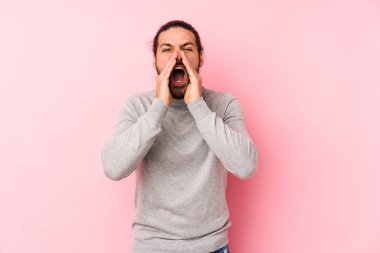 Genç, uzun saçlı adam pembe bir arka planda izole edilmiş, heyecanlı bir şekilde bağırıyor..