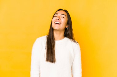 Sarı arka planda izole edilmiş genç bir kadın. Rahatlamış ve mutlu bir şekilde gülüyor. Dişlerini göstererek boynunu geriyor..