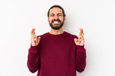 Uzun saçlı genç adam beyaz arka planda izole edilmiş şans dilemek için şans diliyor.