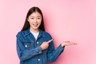 Pembe arka planda poz veren Çinli genç bir kadın..