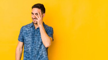 Genç, beyaz bir adam sarı bir alanda izole edilmiş. Kameraya parmaklarıyla göz kırpıyor. Yüzünü kapatmaktan utanıyor..