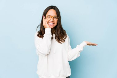 Genç, melez, İspanyol bir kadın avucunun içinde fotokopi alanı tutuyor, el üstünde tutuyor. Şaşırmış ve mutlu..