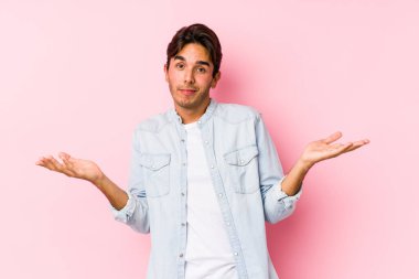 Pembe arka planda poz veren beyaz bir genç şüpheli ve sorgulama sırasında omuz silkiyor..