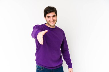 Beyaz arka planda izole edilmiş genç bir adam kameraya elini uzatarak selam veriyor..