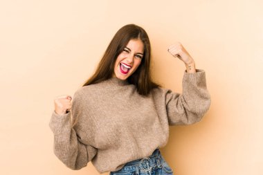 Beyazlı genç kadın bej arka planda izole edilmiş zafer kazandıktan sonra yumruğunu kaldırıyor, kazanan konsept..