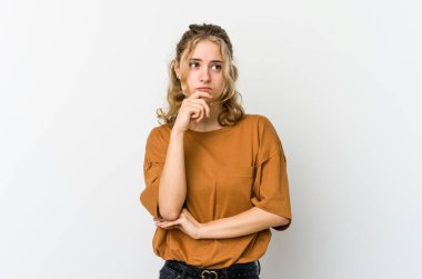 Beyaz arka plandaki genç beyaz kadın düşünüyor ve bakıyor, yansıtıyor, düşünüyor, hayal kuruyor..