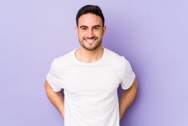 Mor arka planda izole edilmiş genç beyaz adam mutlu, güler yüzlü ve neşeli..