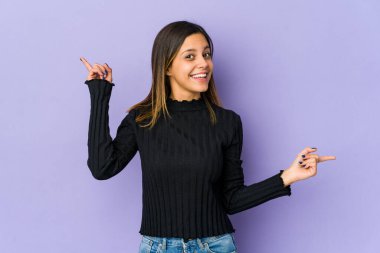 Mor arka planda izole edilmiş genç bir kadın farklı kopya alanlarını gösteriyor, birini seçiyor, parmaklarıyla gösteriyor..