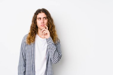 Genç, uzun saçlı bir adam yalnız poz veriyor. Şüpheli ve şüpheci bir ifadeyle yana bakıyor..