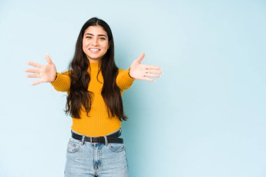 Mavi arka planda izole edilmiş genç Hintli kadın kameraya sarıldığı için kendinden emin hissediyor..