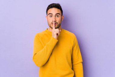 Mor arka planda izole edilmiş genç beyaz bir adam bir sır saklıyor ya da sessizlik istiyor..