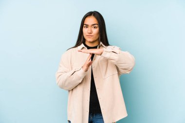 Mavi arka planda izole edilmiş genç bir kadın bir mola hareketi gösteriyor..