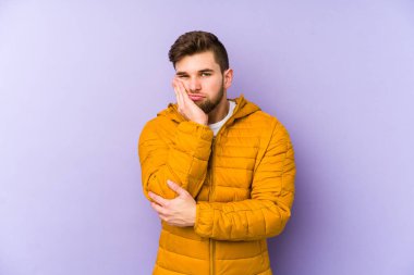 Mor arka planda izole edilmiş, sıkılmış, yorgun ve dinlenmeye ihtiyacı olan genç bir adam..