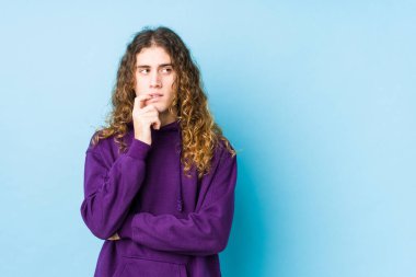 Uzun saçlı adam izole edilmiş poz veriyor. Bir şeyin fotokopi odasına baktığını düşünüyor..