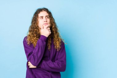 Uzun saçlı adam şüpheli ve şüpheci ifadesiyle yanlamasına poz veriyor..