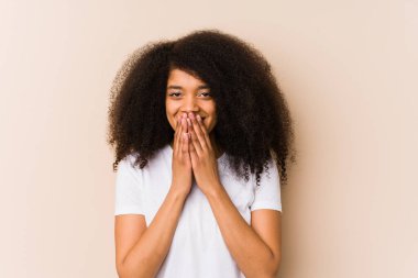 Genç Afrikalı Amerikalı bir kadın bir şeye gülüyor, elleriyle ağzını kapatıyor..