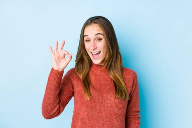 Kafkasyalı genç bir kadın tek başına poz veriyor, göz kırpıyor ve elleriyle iyi bir jest yapıyor..