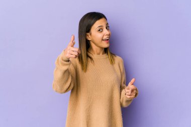 Mor arka planda izole edilmiş genç bir kadın parmaklarıyla öne doğru işaret ediyor..