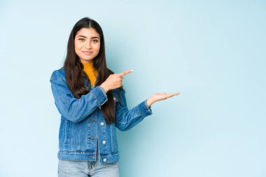 Genç Hintli bir kadın mavi arka planda izole edilmiş..