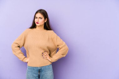 Mor arka planda soyutlanmış, kafası karışmış, şüpheli ve güvensiz genç bir beyaz kadın..