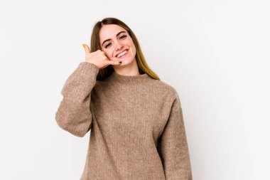 Beyaz arka planda izole edilmiş genç beyaz kadın parmaklarıyla bir cep telefonu hareketi gösteriyor..