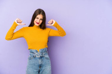 Mor arka planda izole genç beyaz kadın gururlu ve kendinden emin hissediyor, örnek olarak..