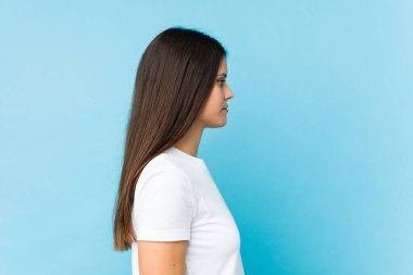 Kafkasyalı genç bir kızın yüzü, mavi bir arka planda izole bir şekilde yakından çekilmiş.