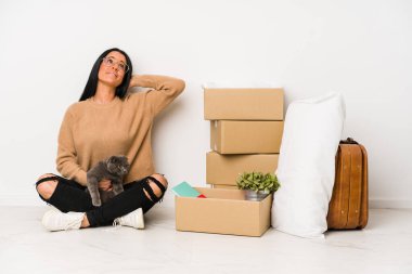 Beyaz arka planda tek başına eve taşınan kadın kafasının arkasına dokunuyor, düşünüyor ve bir seçim yapıyor..