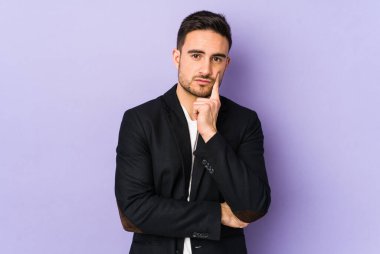 Mor arka planda izole edilmiş genç beyaz adam şüpheli ve şüpheci bir ifadeyle yana bakıyor..