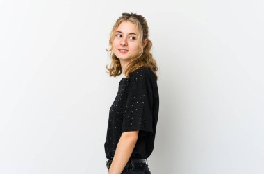 Beyaz arka plandaki genç beyaz kadın gülümseyen, neşeli ve keyifli bir kenara bakar..