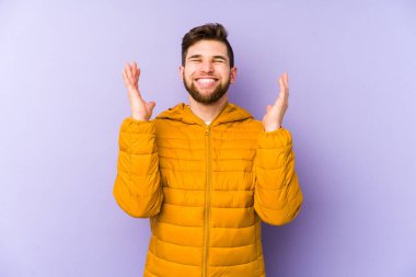 Mor arka planda izole edilmiş genç bir adam neşeli bir şekilde gülüyor. Mutluluk kavramı.